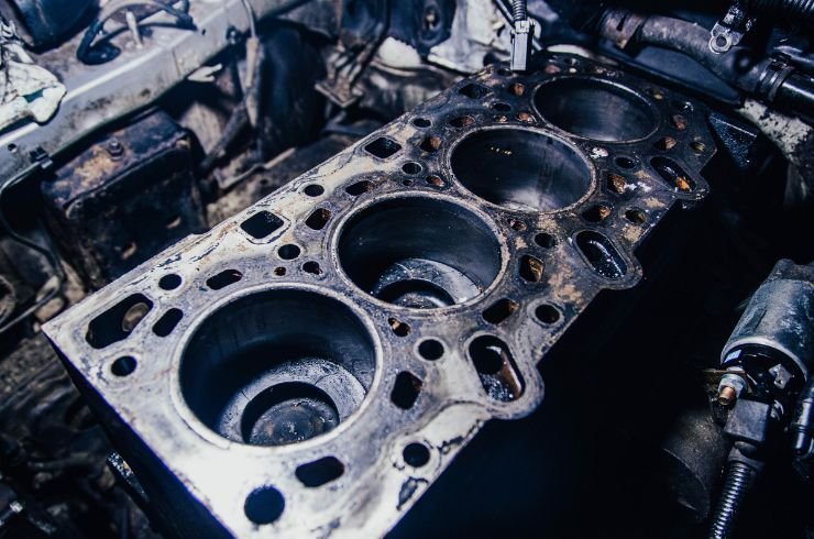 Disassembled car engine block and parts arranged on a garage workbench.