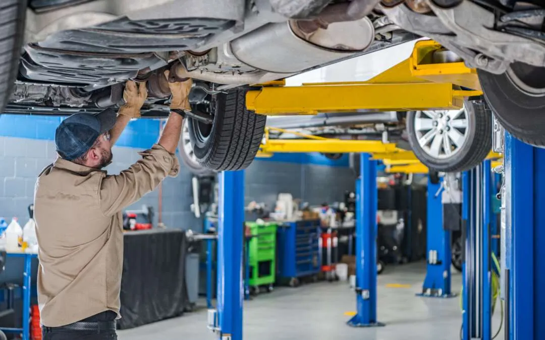 Hands hold a diagnostic scanner near a car engine during vehicle inspection.